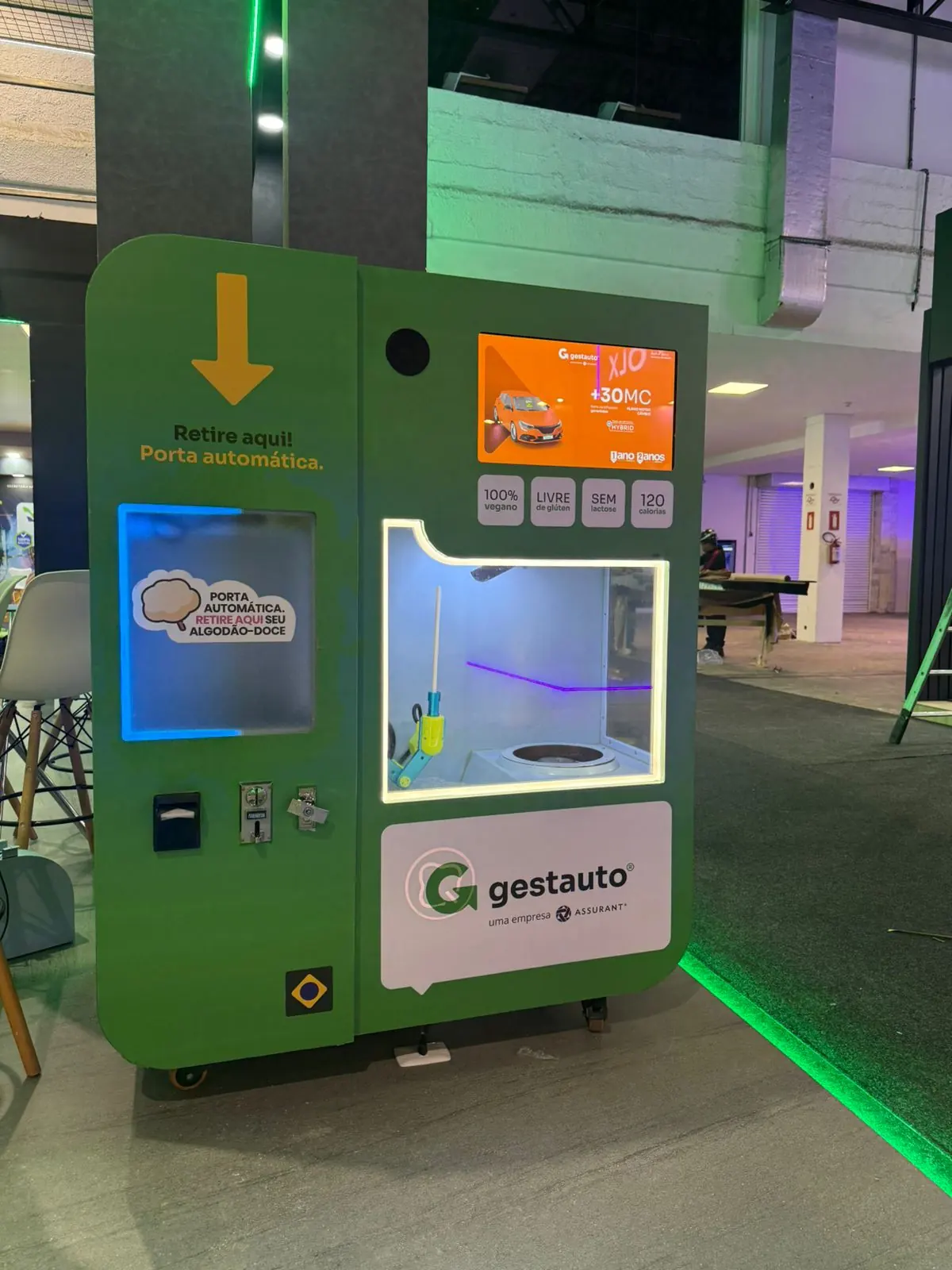 Máquina verde da Gestauto, uma empresa Assurant, com convidados ao redor.